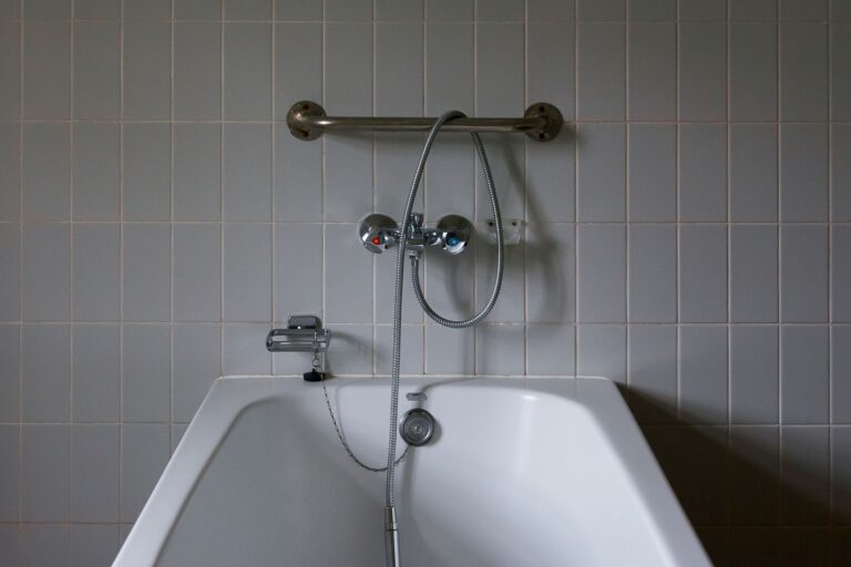 Close-up of a minimalist bathroom featuring a modern bathtub and chrome faucet against tiled walls.