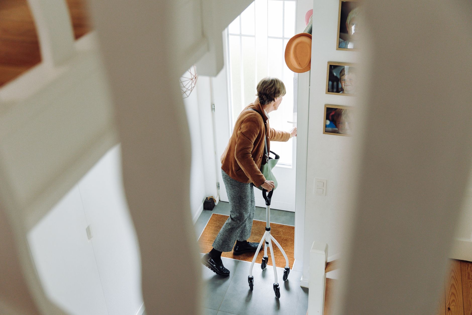 Senior woman using rollator indoors near doorway.